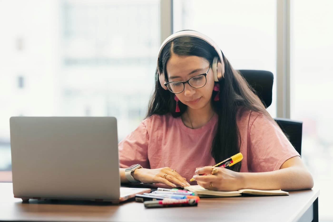 A student in headphones studying at a laptop